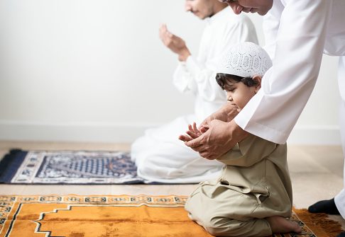 Muslim boy learning how to make Dua to Allah